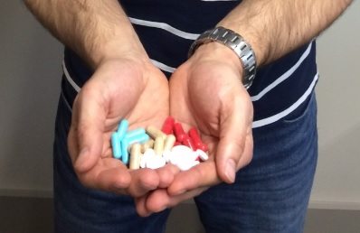 different colored pills in a mans hands
