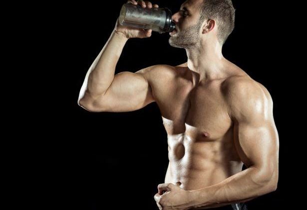 muscular man drinking a supplement