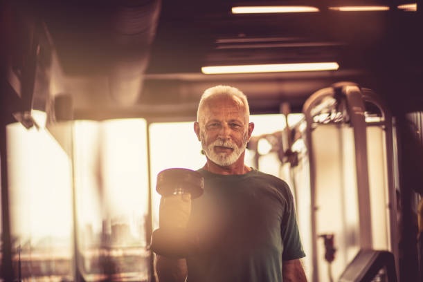 an older man lifting a dumbbell in a gym