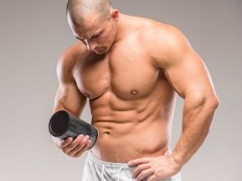 muscular man looking at the ingredients of a supplement bottle