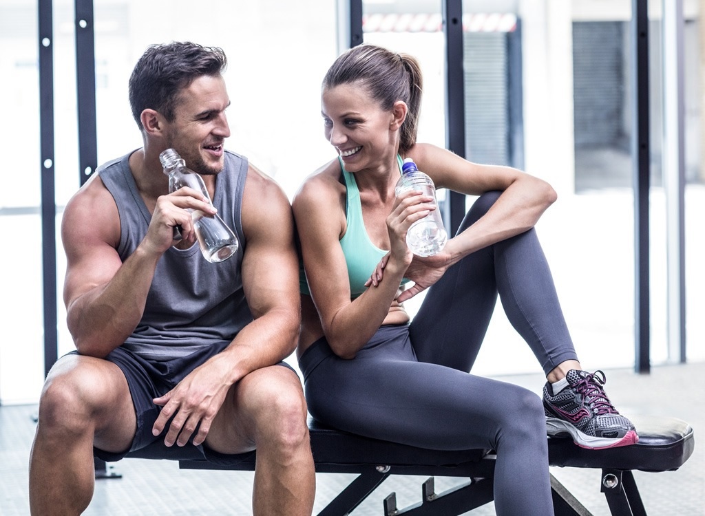 smiling fit man and woman in the gym resting 