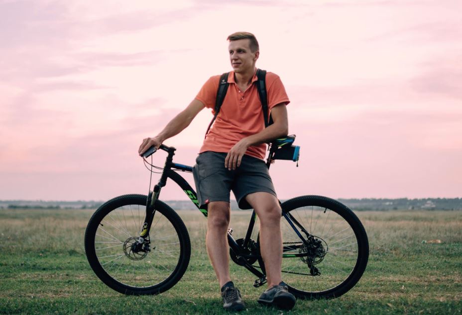 man leaning against bicycle looking wistful